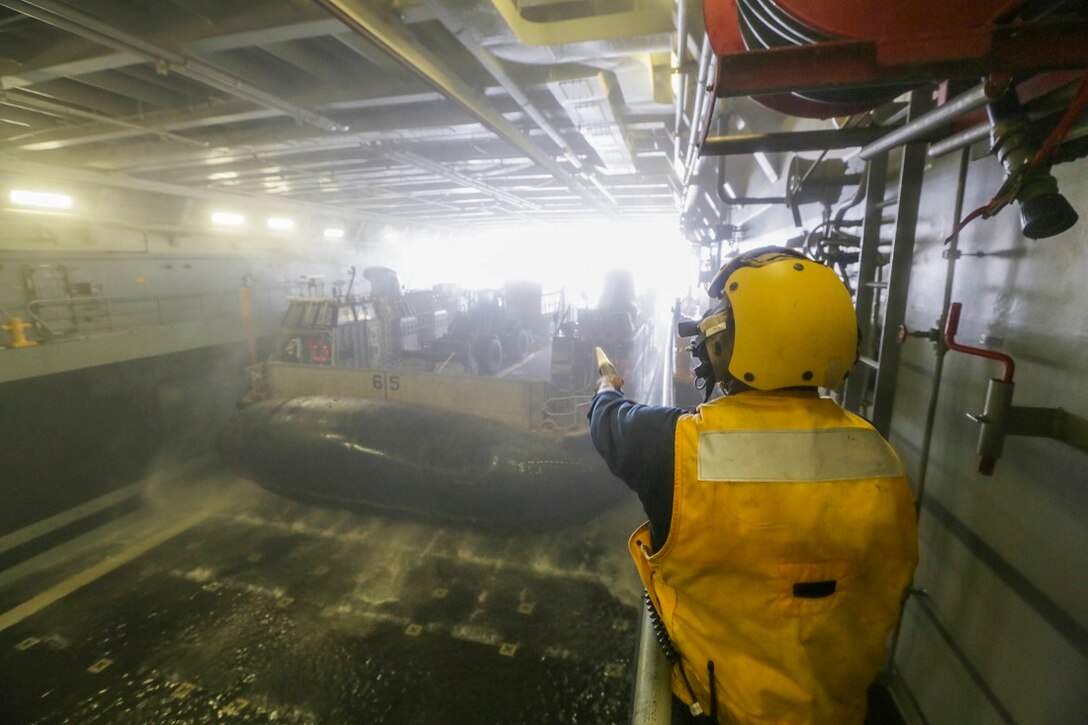 ARABIAN SEA (July 20, 2015) U.S. Navy Petty Officer 3rd Class Keith Blair signals a landing craft, air cushion to depart from the well deck of the amphibious transport dock ship USS Anchorage (LPD 23).  Blair is a boatswain's mate aboard the Anchorage.  Marines and sailors disembarked the Anchorage to conduct training in Djibouti.  BLT 3/1 is the ground combat element of the 15th MEU, is conducting training ashore in Djibouti to maintain the skills they developed during their pre-deployment training cycle and ensure they are prepared to support regional security while deployed to the U.S. 5th Fleet area of operations. (U.S. Marine Corps photo by Sgt. Jamean Berry/Released)