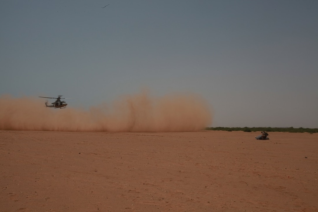 CAMP LEMONNIER, Djibouti (July 23, 2015) A U.S. Marine with the Force Reconnaissance Detachment, 15th Marine Expeditionary Unit, re-packs his parachute after a successful landing, as a UH-1Y Venom lands to pick up the next wave of jumpers. The Force Recon Det is ashore in Djibouti sustaining their parachute and diving skills during the 15th MEU’s deployment in support of maritime security operations and theater security cooperation efforts in the U.S. 5th Fleet area of operations (U.S. Marine Corps photo by 1st Lt. Allison Burgos/Released)