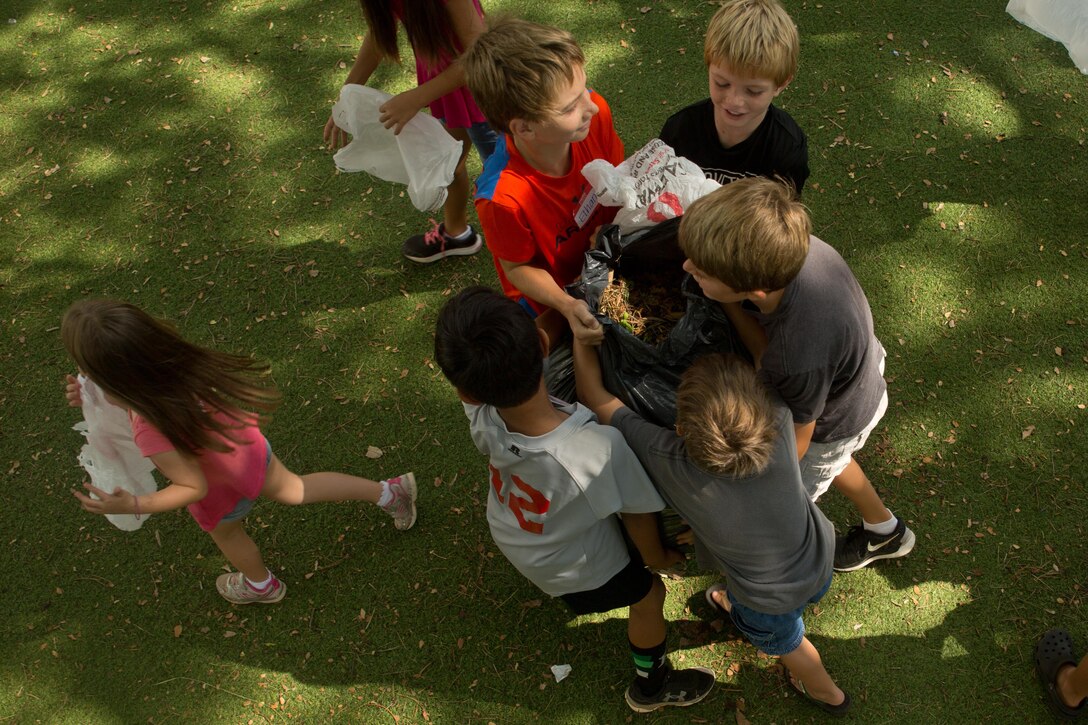Students participating in the summer Dream Company program work together to hoist a child-sized bag of fallen leaves during the Jump Start Aikahi clean-up at Aikahi Elementary School, July 22, 2015. This event is a first for the summer cleaning program, put into place by the new temporary principal Keoki Fraser. When service members from Marine Corps Base Hawaii help the community it helps the overall mission of the base to provide facilities, programs and services in direct support of units, individuals and families in order to enhance and sustain combat readiness for all operating forces and tenant organizations aboard the installation. (U.S. Marine Corps photo by Cpl. Khalil Ross/Released)