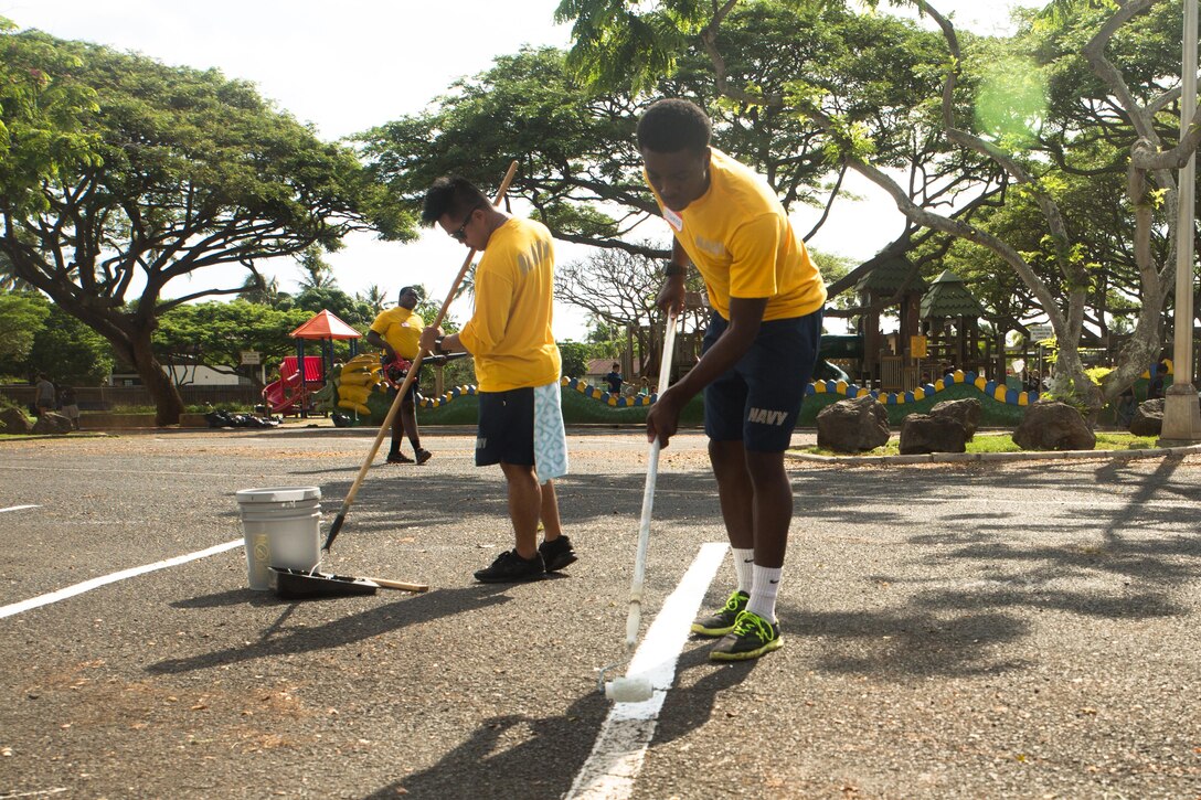 Seaman Johnta Minor, a boatswain with Water Front Operations, applies a fresh coat of paint to the fading parking lines during the Jump Start Aikahi clean up at Aikahi Elementary School, July 22, 2015. More than 50 students, service members from Marine Corps Base Hawaii, and local volunteers from the Kailua community came together to clean up Aikahi Elementary School before the start of the new school year. When service members from Marine Corps Base Hawaii help the community it helps the overall mission of the base to provide facilities, programs and services in direct support of units, individuals and families in order to enhance and sustain combat readiness for all operating forces and tenant organizations aboard the installation. (U.S. Marine Corps photo by Cpl. Khalil Ross/Released)