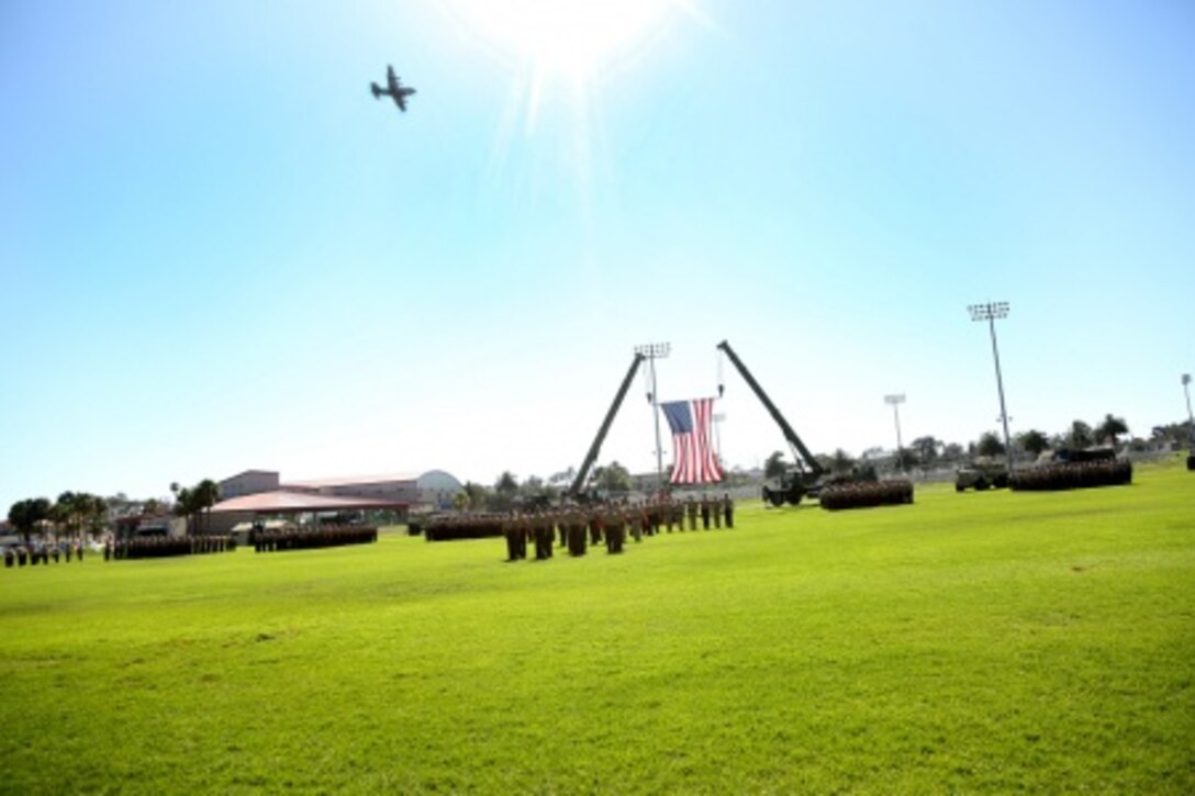 A C-130 aircraft flies by during the 1st Marine Logistics Group Change of Command Ceremony aboard Camp Pendleton, Calif., July 24, 2015. Major Gen. Vincent A. Coglianese relinquished command of 1st MLG to Brig. Gen. David A. Ottignon during a change of command ceremony at the 11 Area Parade Field, July, 24, 2015. The ceremony included the passing of the 1st MLG colors, remarks from the incoming and outgoing commanders, performances by the 1st Marine Division Band, a C-130 flyover and static displays depicting the various aspects of the MLG.