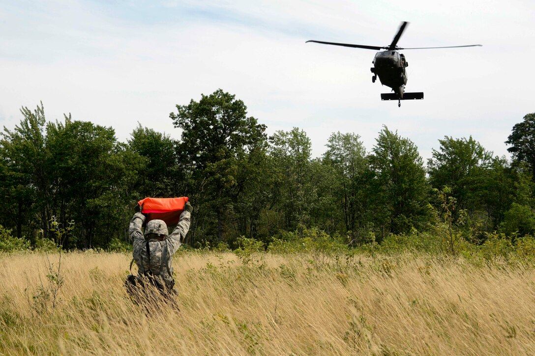 A Michigan Army National Guardsman guides a UH60 Black Hawk helicopter into landing position