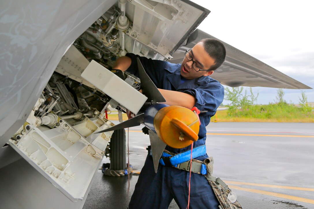 Air Force Airman 1st Class Kenny Huynh secures an inert AIM-9 Sidewinder missile to an F-22 Raptor during a load crew competition on Joint Base Elmendorf-Richardson, Alaska, July 17, 2015. 
