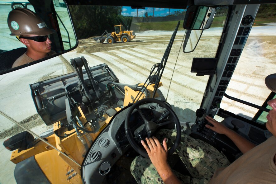 U.S. Navy Seaman Jacob Helfert, Naval Mobile Construction Battalion 5 equipment operator constructionman, uses heavy machinery to push debris away from a crater during joint airfield damage repair training on Kadena Air Base, Japan, July 23, 2015. The training gave U.S. Air Force and Navy participants the opportunity to gain familiarity with one another while practicing skills they could potential implement in a wartime environment. (U.S. Air Force photo by Staff Sgt. Maeson L. Elleman)