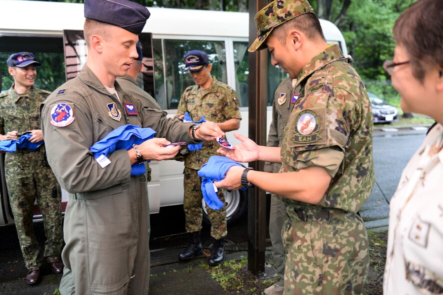 Capt. William Poeschl, 459th Airlift Squadron current operations officer, presents a 459 AS patch and t-shirt to Capt. Tomonari Kanatsuka, Japan Ground Self-Defense Force UH1-J pilot, at Tachikawa Air Base, Japan, July 16, 2015. The tour enhanced the US-Japan bilateral relationship, which is a key part of stability in Indo-Asia Pacific region. (U.S. Air Force photo by Airman 1st Class Elizabeth Baker/Released)