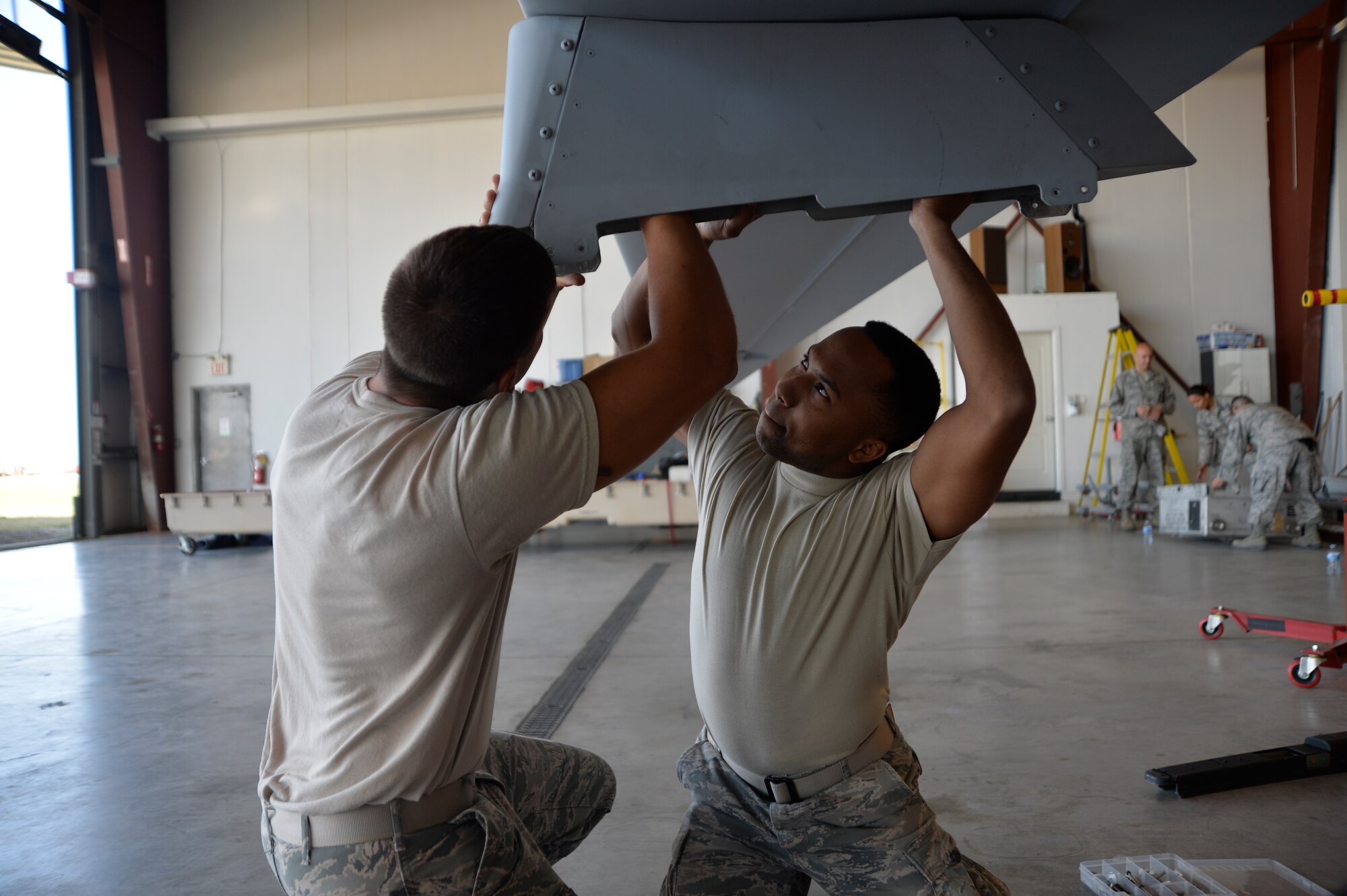 Senior Airman Nicholas Villa, 432nd Aircraft Maintenance Squadron weapons load crew member, left, and Senior Airman Shamai Bell, 432nd AMXS avionics technican assemble the weapons pylon of an MQ-1 Predator July 25, 2015, in Lethbridge, Alberta province, Canada. The MQ-1 Predator participated in the 2015 Lethbridge International Airshow as a static display where spectators could ask the maintenance, intelligence, sensor operators, and pilots questions about the aircraft. (U.S. Air Force photo by Airman 1st Class Christian Clausen/Released)