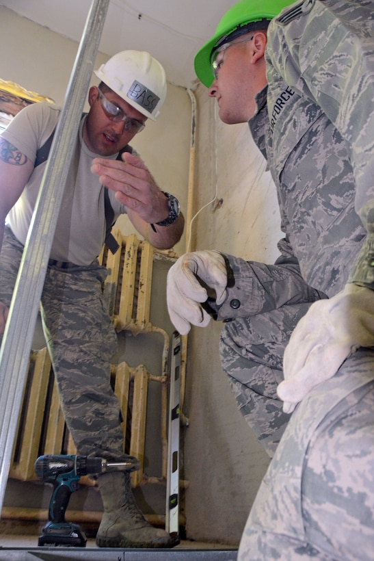 Master Sgt. Lonnie Bass and Senior Airman Gary Keim  plan their dry-wall installation at an orphanage building in Daugavpils, Latvia. (Photo by Master Sgt. Allen Pickert, 190th Public Affairs)