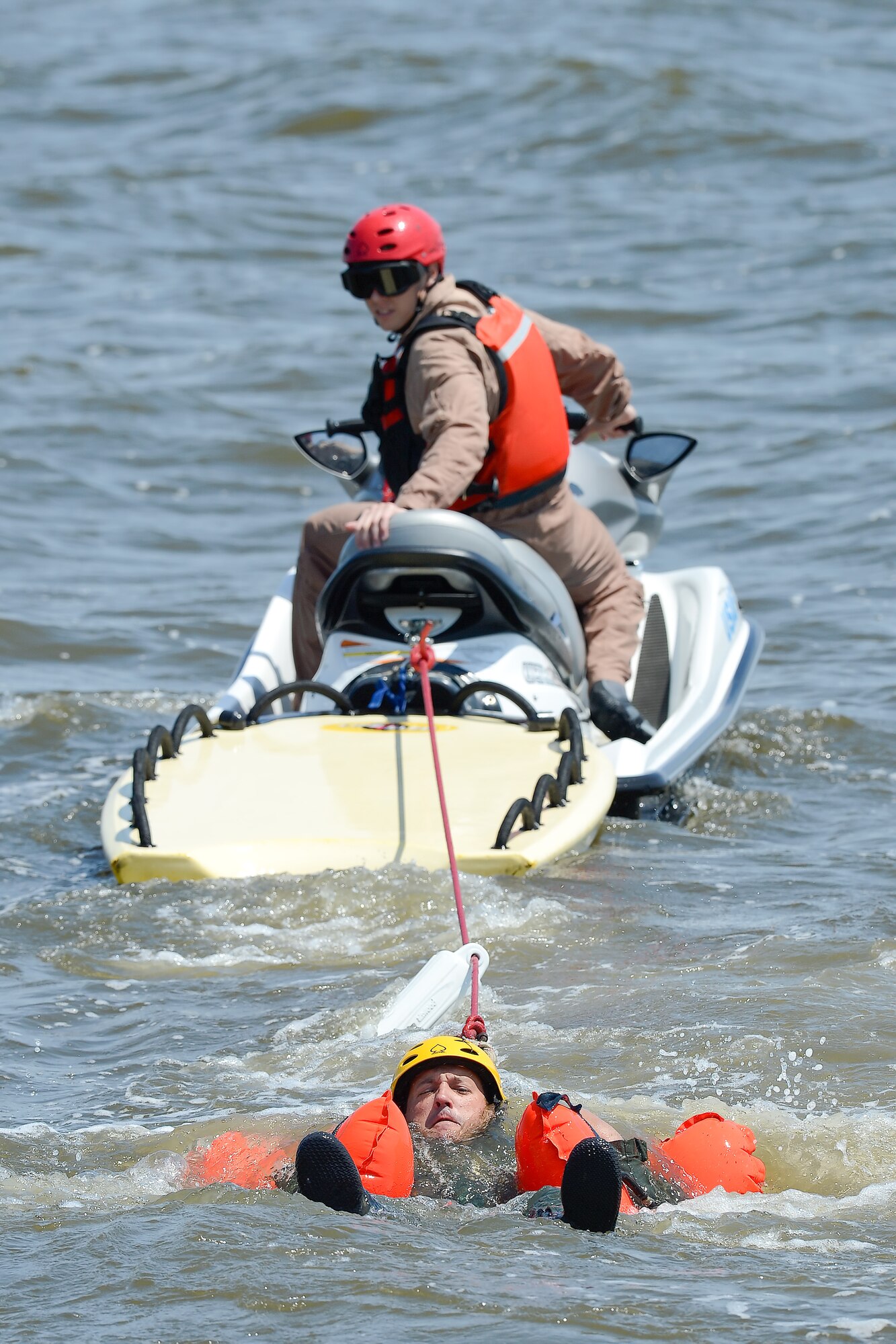 Water survival refresher trainee, Master Sgt. Joshua Mal, 3d Airlift Squadron C-17A Globemaster III loadmaster, keeps his head above water as Staff Sgt. Adam Ellerd, 436th Operations Support Squadron Survival, Evasion, Resistance and Escape Operations NCO in charge, looks over his shoulder from a personal watercraft to see when and if Mal successfully releases from his harness July 17, 2015, near Dover Air Force Base, Del. Mal and other students had to find and release their torso harness fittings while being towed through the water to simulate being dragged by their canopy after landing in water. (U.S. Air Force photo/Greg L. Davis)