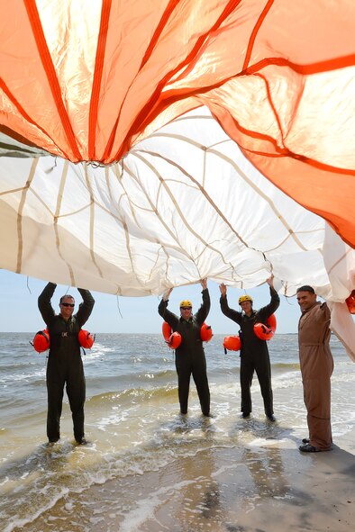 Technical Sgt. Joseph Monreal, 436th Operations Support Squadron Survival, Evasion, Resistance and Escape Operations flight chief, right, and water survival training students hold a C-9 round parachute canopy with orange and white panels above their heads as they prepare to walk it in to the water of the Delaware Bay without it becoming tangled during aircrew water survival refresher training July 17, 2015, near Dover Air Force Base, Del. Once the canopy was in the water each student had a chance to gain confidence in their ability to get out from under a water soaked canopy by following a seam to the edges. (U.S. Air Force photo/Greg L. Davis))