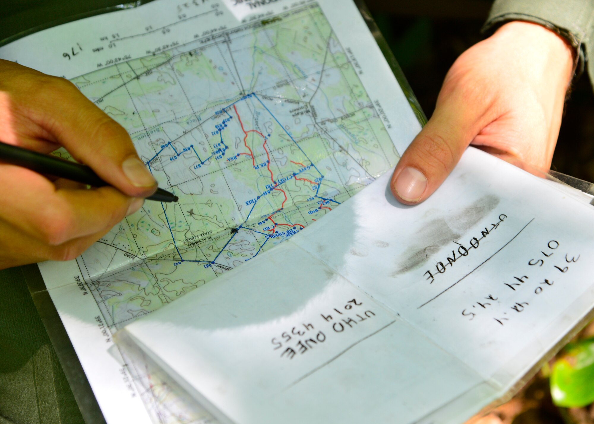 Senior Airman Leo Avila, 709th Airlift Squadron C-5M Super Galaxy engineer, uses coordinates to mark his crew’s position on a map during a combat survival training exercise July 16, 2015, at the Blackbird State Forest near Smyrna, Del. The crew was equipped with a compass and a map to navigate several miles of woodland and marshy terrain during the exercise. (U.S. Air Force photo/Airman 1st Class William Johnson)