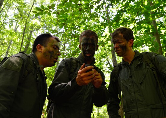 Senior Airman Leo Avila, 709th Airlift Squadron C-5M Super Galaxy engineer, left, Capt. Rob Willoughby, 9th AS C-5M pilot, center, and Maj. Brian Hint, 709th AS C-5M pilot, right, look at GPS coordinates before radioing in their location to friendly rescue forces during a combat survival training exercise July 16, 2015, at the Blackbird State Forest near Smyrna, Del. The crew was required to evade enemy forces while maintaining radio communications with rescue personnel during the training exercise. (U.S. Air Force photo/Airman 1st Class William Johnson)