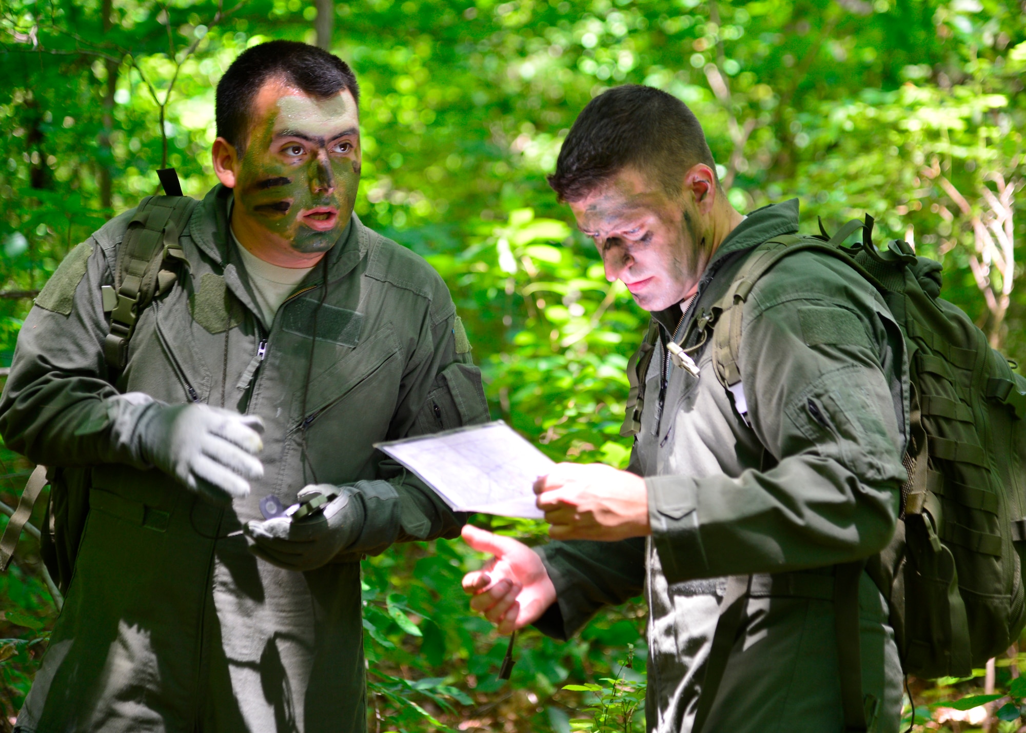 Senior Airman Leo Avila, 709th Airlift Squadron C-5M Super Galaxy engineer, left, and Senior Airman Dan Bates, 9th AS C-5M loadmaster, right, use a compass and a map to navigate to a checkpoint during a combat survival training exercise July 16, 2015, at the Blackbird State Forest near Smyrna, Del. Avila and Bates navigated with three other members of their team through several miles of forest to be rescued by friendly forces after escaping from enemy combatants. (U.S. Air Force photo/Airman 1st Class William Johnson)