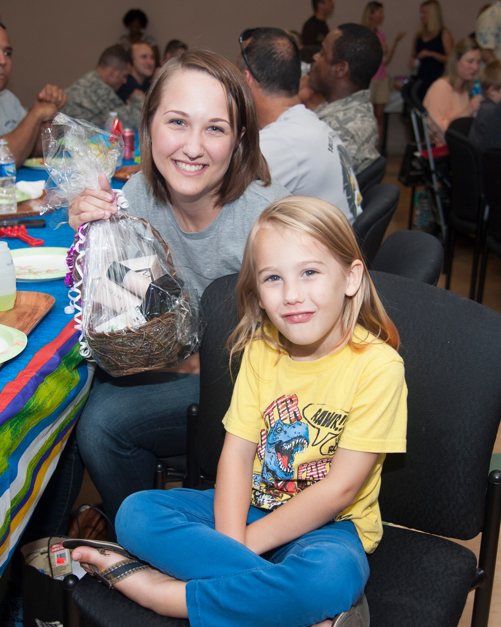 Andrea Olaya-Gonzalez, wife of Staff Sgt. Andres Olaya-Gonzalez, 436th Airlift Wing Staff Judge Advocate paralegal, and their son, Jude, present the raffle winnings during the Deployed Families Dinner July 23, 2015, at the Youth Center on Dover Air Force Base, Del. Andrea won cosmetics which were donated to the Airman & Family Readiness Center. (U.S. Air Force photo/Senior Airman Jared Duhon) 
