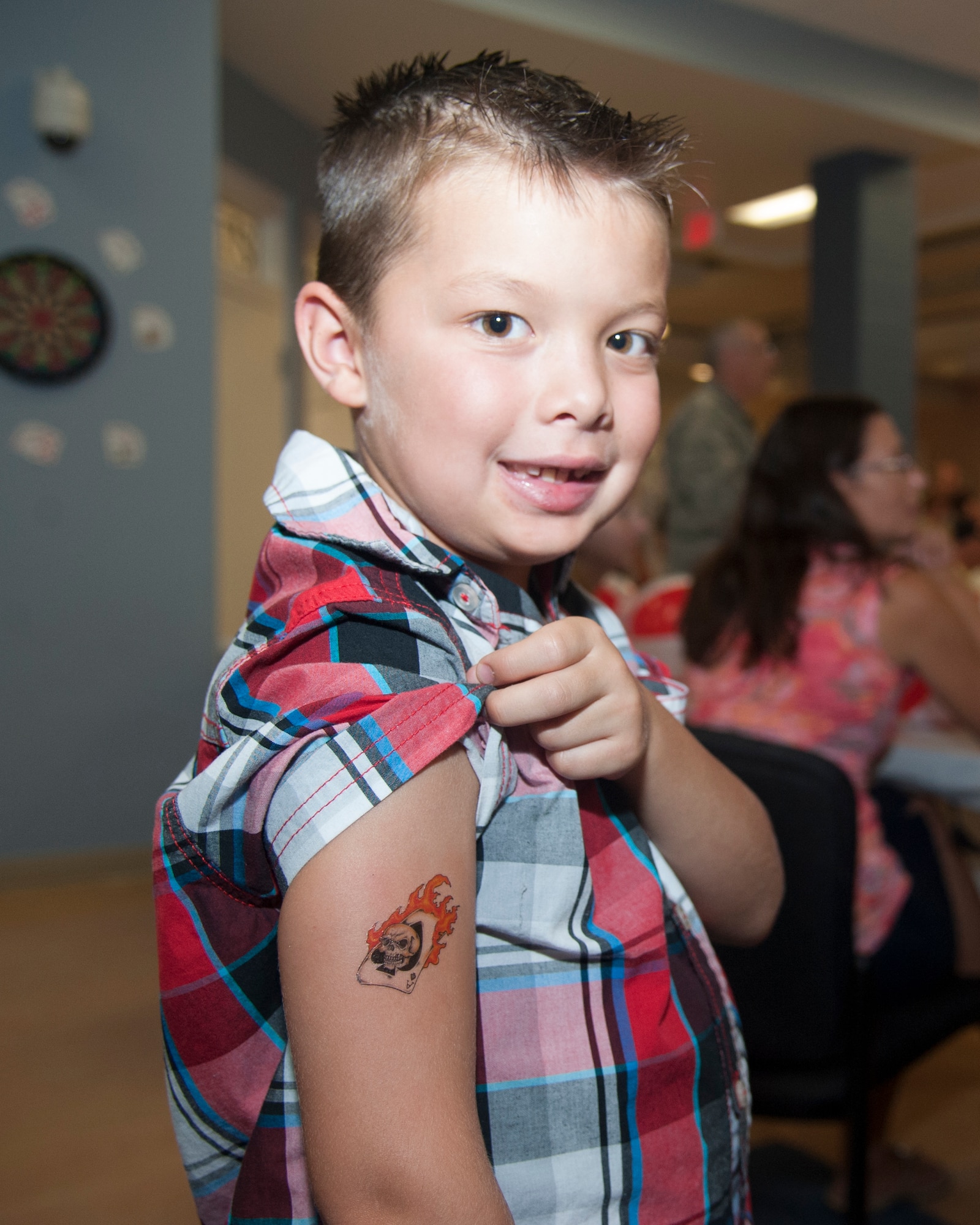 Mason Heathington, son of Tech. Sgt. Kyle Heathington, 436th Aerial Port Squadron, shows off a temporary tattoo during the Deployed Families Dinner July 23, 2015, at the Youth Center on Dover Air Force Base, Del. The tattoos were provided by the Hogs for Heroes foundation. (U.S. Air Force photo/Senior Airman Jared Duhon) 