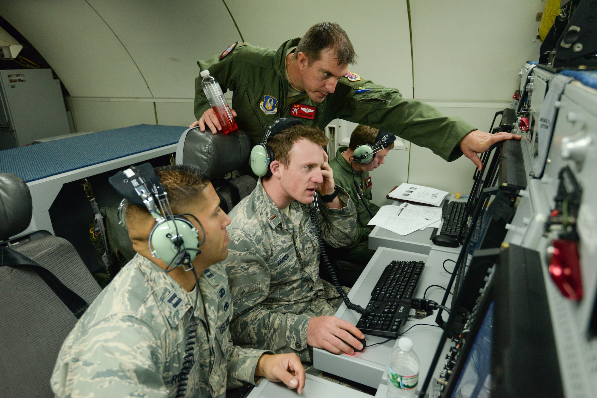 Maj. Phil Schredl, an air weapons officer assigned to the 513th Operations Support Squadron, shows upgraded software on board an E-3G Sentry Block 40/45 to 2nd Lt. Ryan Kramer and Capt. Jeff Rodriguez, both E-3 program managers, July 18 during a training mission. The 513th Air Control Group invited eight program managers on board to see the product of their work and to discuss future improvements to the Airborne Warning and Control System aircraft. (U.S. Air Force photo by Staff Sgt. Caleb Wanzer)