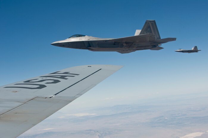 Two F-22 Raptors assigned to the 95th Fighter Squadron, Tyndall Air Force Base, Fla., fly in formation as they wait on a fellow wingman to finish refueling from a KC-135 Stratotanker assigned to the 22nd Air Refueling Wing, McConnell AFB, Kan., during a Red Flag 15-3 training mission over the Nevada Test and Training Range, July 24, 2015. KC-135s are responsible for refueling all aircraft during Red Flag with approximately 20 units participating in 15-3. (U.S. Air Force photo by Airman 1st Class Jake Carter) 