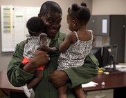 Tech. Sgt. Uwemediimo Essien, 41stt Rescue Squadron special missions aviator, plays with his daughters before going out to perform pre-flight inspections on an HH-60G Pave Hawk July 21, 2015, on Moody Air Force Base, Ga. Essien said it was important to him to find the balance between his career and family and he‘s lucky to have found someone who understands his job. (U.S. Air Force photo/Tech. Sgt. Zachary Wolf/Released)