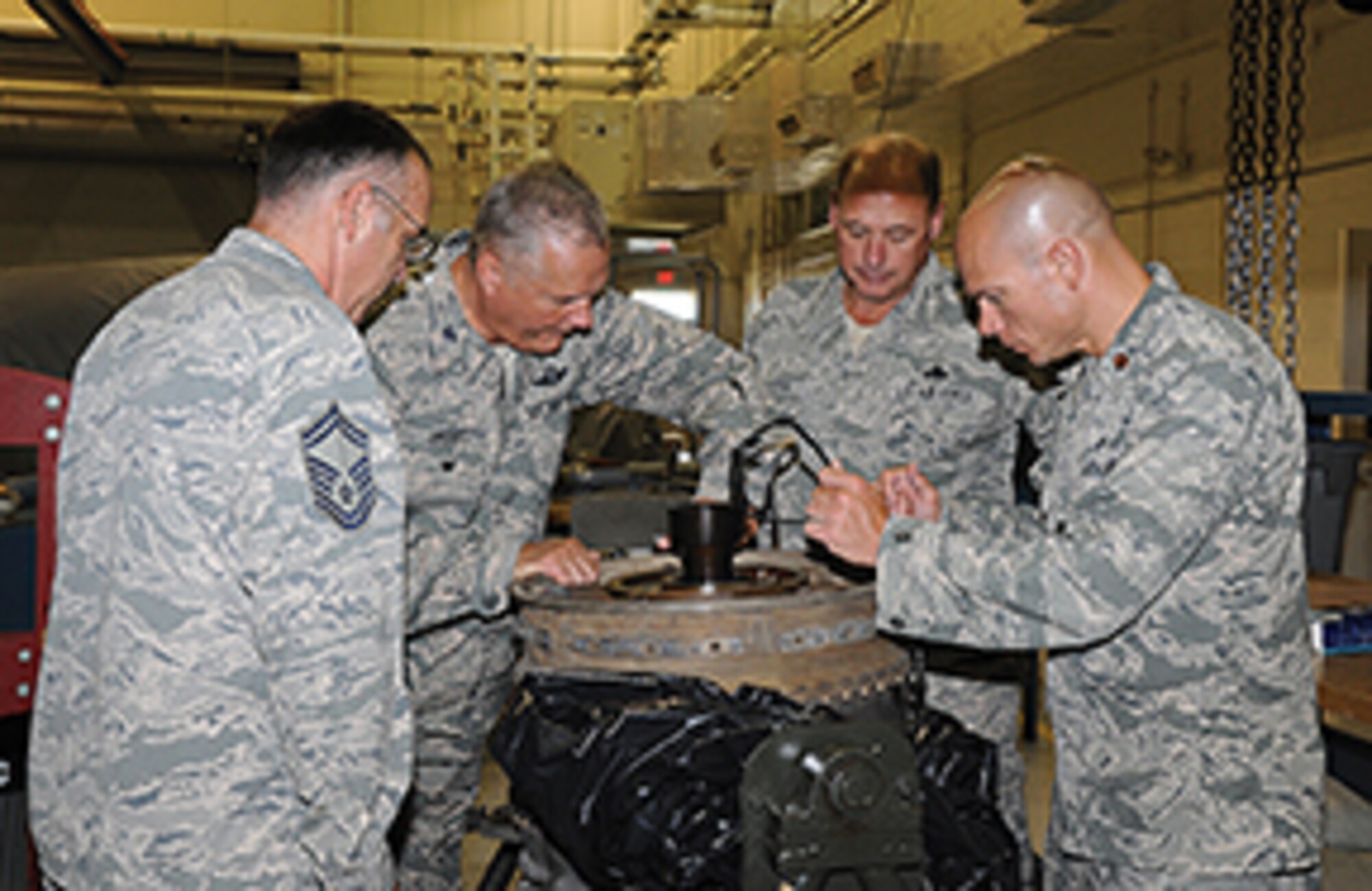 Senior Master Sgt. Michael Smith of the 908th MXS Propulsion Shop, far left, Senior Master Sgt. Dain Payton, MXS Superintendent, second from right; and MXS Operation Officer Maj. Brian Horton, far right, show Col. Jimmie Brooks, new 908th Airlift Wing Vice Commander, a cracked C-130 engine turbine section.