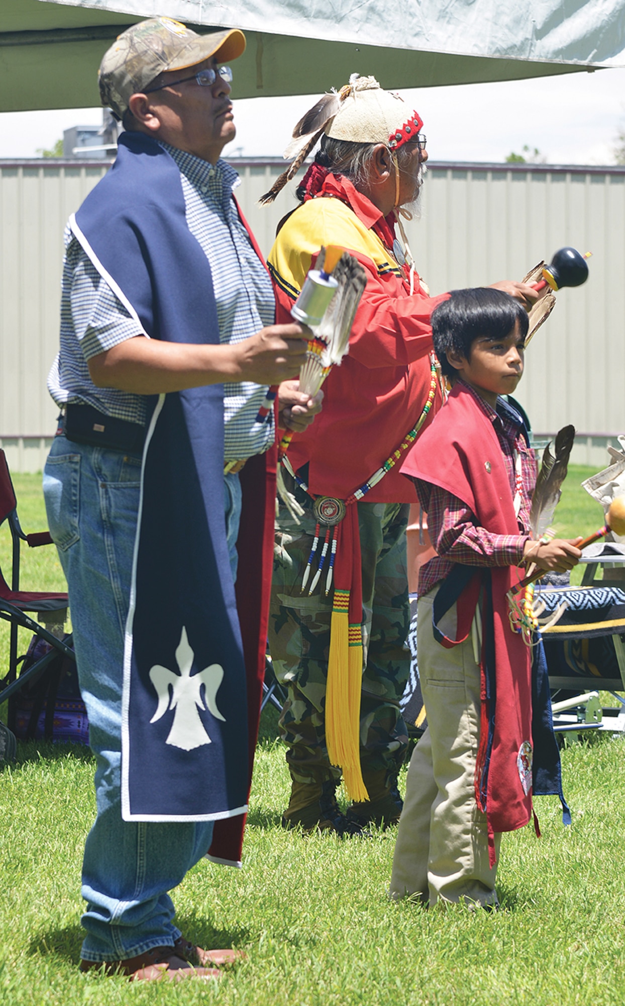 Jacob Begay, 10, from Window Rock, Arizona, and color guard William “Shorty” Lewis, far left, from Zuni Pueblo perform at the 10th Annual VA Veterans Gourd Dance July 18. The dance celebrates warriors’ victories and helps the healing process by providing fellowship and reminding veterans they are not alone, nor are they forgotten.  (Photo by Todd Berenger)