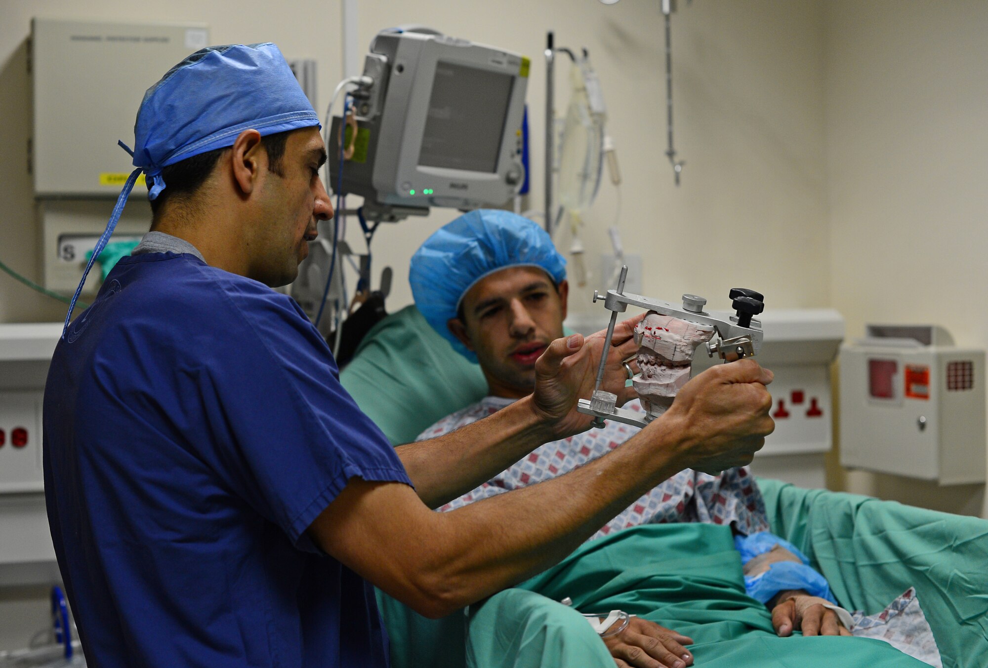 Lt. Col. Khurram Shahzad, 48th Dental Squadron oral maxillofacial surgeon, shows a jaw anatomy model to Senior Airman Trevor McBride, 48th Fighter Wing Public Affairs photojournalist, before an orthognathic facial surgery in the hospital at Royal Air Force Lakenheath, England, July 9, 2015. The procedure is performed to correct jaw and facial conditions, which can affect breathing, induce sleep apnea and cause difficulty eating. (U.S. Air Force photo by Senior Airman Erin O’Shea/Released) 