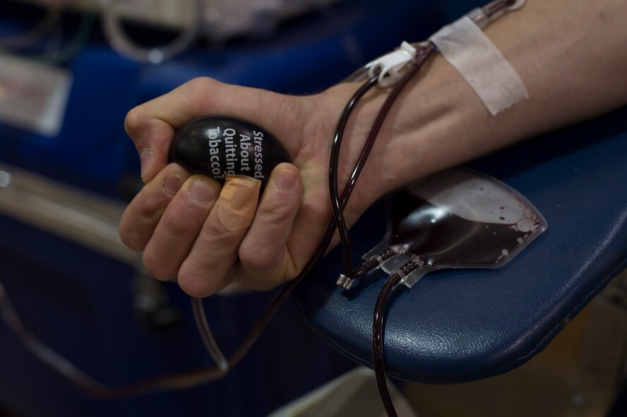 U.S. Air Force Capt. Nicholas Gumley, 93d Air Ground Operations Wing comptroller, squeezes a stress ball to increase blood circulation during a blood drive July 22, 2015, at Moody Air Force Base, Ga. Gumely was one of several service members to donate blood through a haemonetics machine that sorts blood cells and plasma. (U.S. Air Force photo by Staff Sgt. Eric Summers Jr./Released)