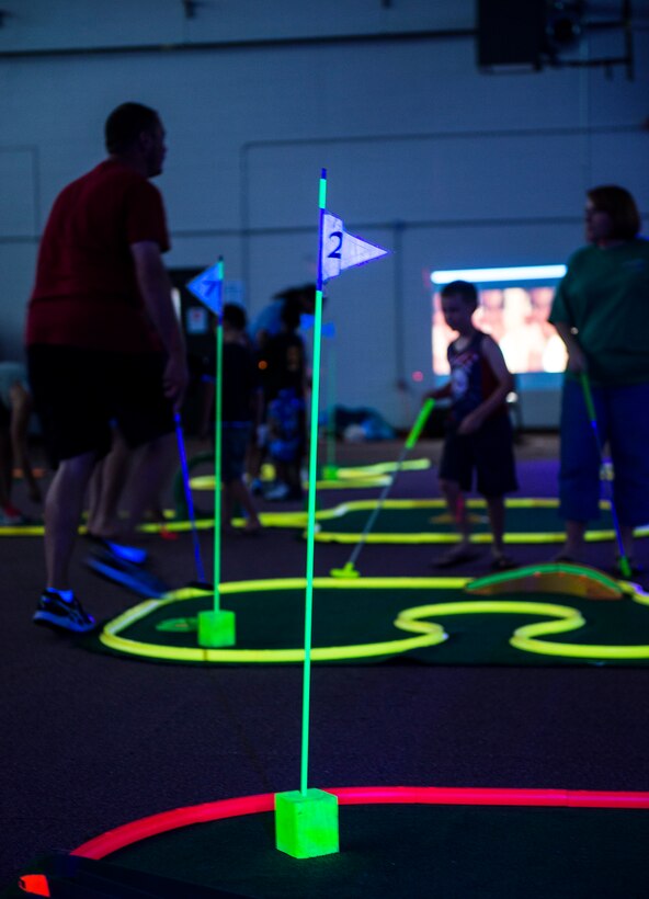 Guests in attendance play miniature golf during Recharge for Resiliency Glow in the Dark Miniature Golf July 24, 2015, at Moody Air Force Base, Ga. Approximately 120 guests attended the event which was designed to build and sustain Airmen and their families’ resiliency through various programs. (U.S. Air Force photo by Airman 1st Class Ceara Tinsley/Released)
