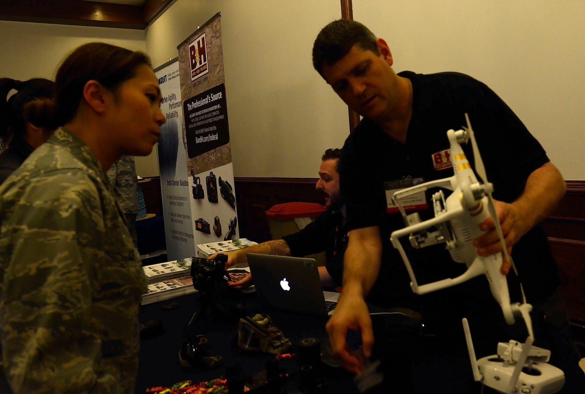 Maj. Phuochue Le, U.S. Air Forces in Europe A6 engineering and architecture branch chief, listens to a representative from B&H Photo, Video, Pro Audio during the Armed Forces Communications-Electronics Association’s Technology Exposition July 20, 2015, at Ramstein Air Base, Germany. The purpose of the two- day expo was to provide a venue for Airmen and civilians to see firsthand the technology and capabilities available from various companies.  (U.S. Air Force photo/Airman 1st Class Tryphena Mayhugh)