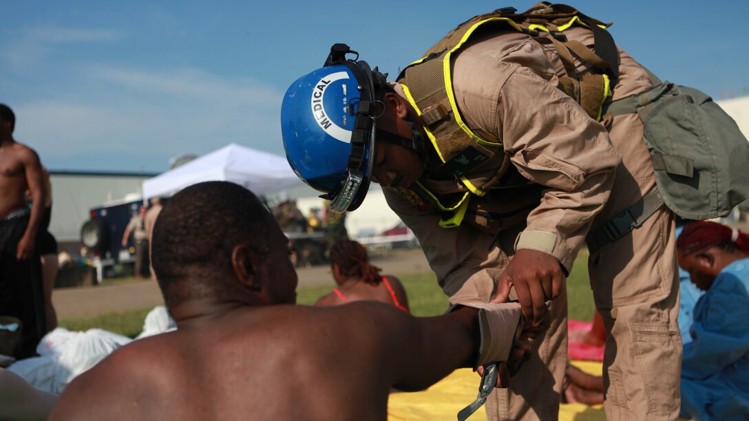 Petty Officer 3rd Class Jamal Porter, a corpsman with the Medical Team, splints a broken arm of a civilian role player during the 36-hour continuous operation as part of Exercise Scarlet Response 2015 at Guardian Centers in Perry, Georgia, July 23.  Corpsman triage victims after they are washed down in the decontamination tent.  If a victim has a severe injury then they are taken to the medical tent where they are put under machines and looked at further. 
