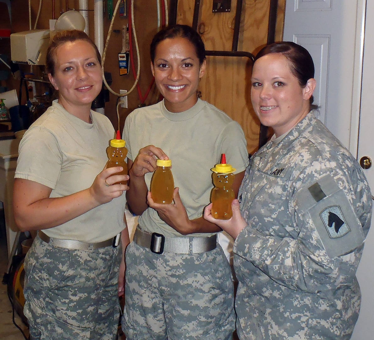 Kentucky Guard members Army Sgt. 1st Class Crystal Dunn, Army Capt. Varinka Barbini and Army Staff Sgt. Catherine Corson, of Agribusiness Development Team 4, hold bottles of honey they processed while training with Jim Cline, a retired chief warrant officer 4 who served more than 30 years in the Kentucky Guard as an aviator. The Guard members are scheduled to deploy next year and teach beekeeping skills as part of the ADT mission to support and impact sustainability and economic development of the Afghan people.