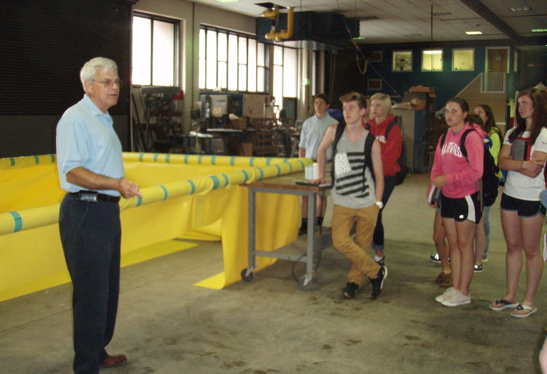 CRREL Research Civil Engineer Leonard Zabilansky explains to visiting St. Paul’s School Advanced Studies Program students the design and fabrication of the isolation hoop (yellow item in background), and where and how it will be used to help researchers learn more about detecting oil under an ice sheet.