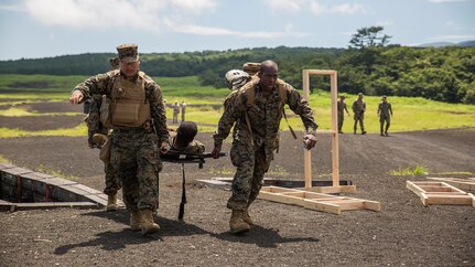 COMBINED ARMS TRAINING CENTER CAMP FUJI, Japan (July 20, 2015) - Hospital Corpsman Mc Joe Evans Bautista, left, and Hospital Corpsman 3rd Class Trevor A. Tisby, right, stationed with Combat Logistics Company 36 aboard Marine Corps Air Station Iwakuni, Japan, carry Sgt. Kendrick Moore, a motor transport operator with CLC-36, to a safety vehicle during Exercise Dragon Fire 2015.  Dragon Fire enables Marines and Sailors to engage their combat mindset to prepare for the mental and physical stresses of a combat zone. Moore simulated an unexpected injury during this training scenario that allowed the corpsmen to respond as if there was a real emergency.  