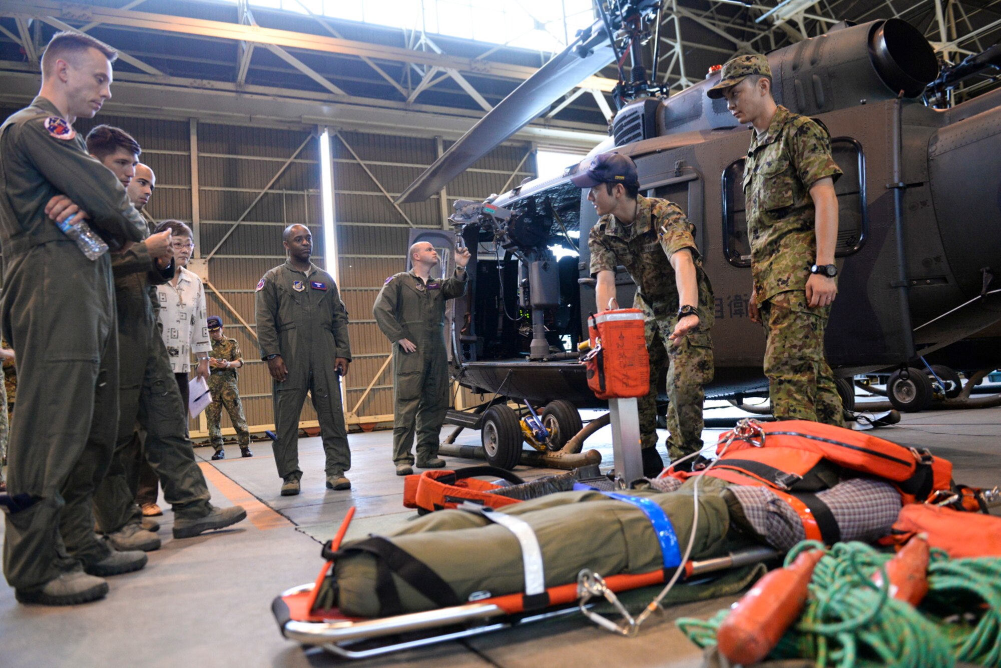 Japan Ground Self-Defense Force Sgt. Miyauchi with the demonstrates a rescue hoist and stokes litter to aircrew with the 459th Airlift Squadron at Tachikawa Air Base, Japan, July 16, 2015. The rescue hoist, used in search and rescue operations, is a capability which members of the 459th AS are in the process of gaining. (U.S. Air Force photo by Airman 1st Class Elizabeth Baker/Released)