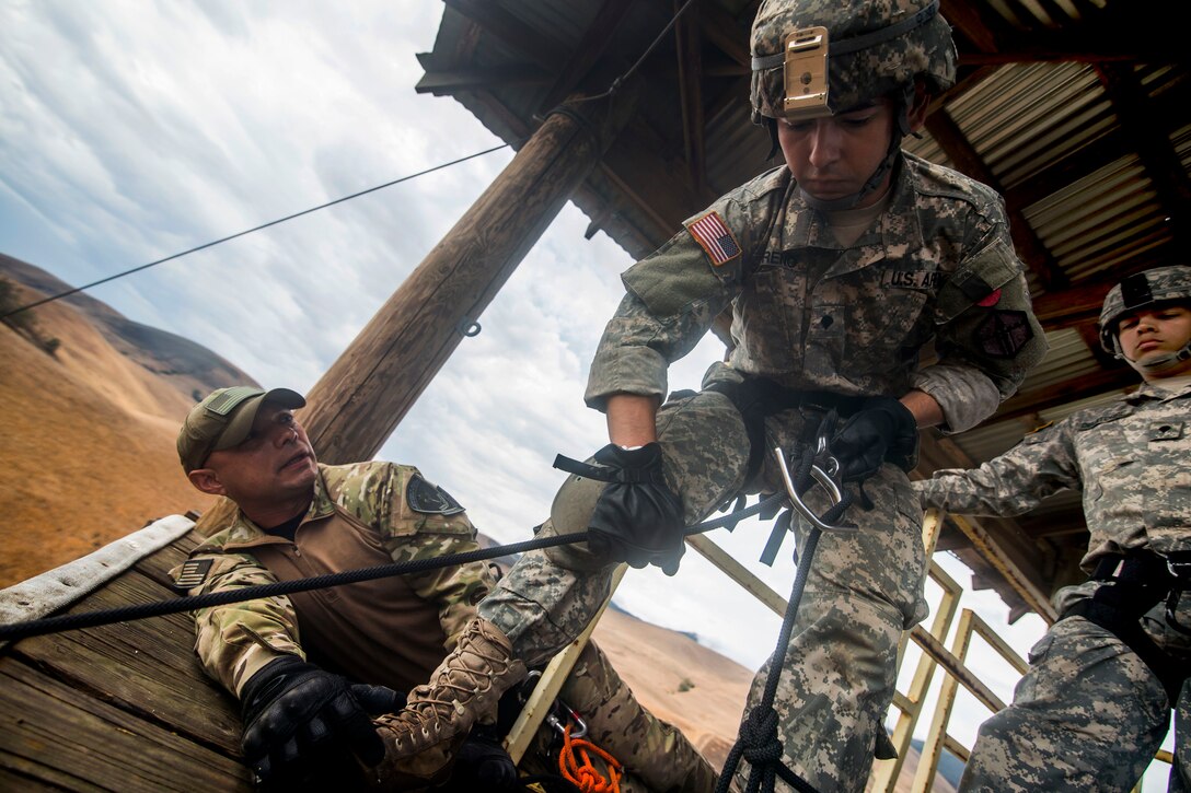 A rappel master, left, assists a soldier as he checks his rope before rappelling down a 100-foot tower during a sapper leader course on Camp San Luis Obispo in San Luis Obispo County, Calif., July 19, 2015. The rappel master is assigned to the U.S. Department of Justice, Special Operations Response Team. 