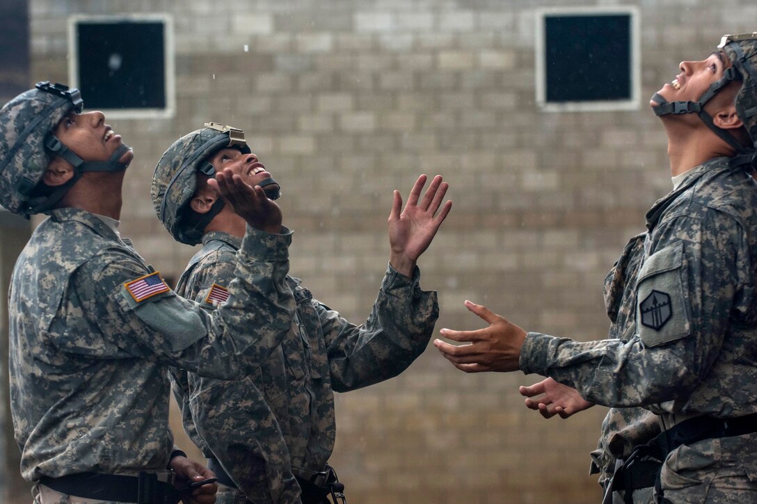 Soldiers try to catch rain drops from a 100-foot rappel tower while waiting for training to resume during a sapper leader course on Camp San Luis Obispo in San Luis Obispo County, Calif., July 19, 2015.  
