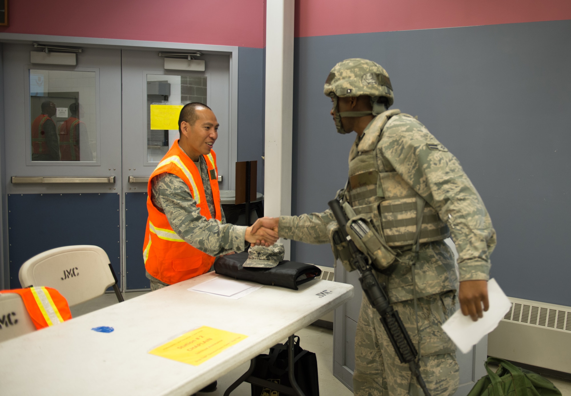 U.S. Air Force Capt. Angeles DeLeon, a 354th Fighter Wing Protestant chaplain, greets an Airman who is simulating deploying during an operational readiness exercise July 28, 2015, at Eielson Air Force Base, Alaska. Several base agencies including the chapel, finance, legal and medical group came together for a pre-deployment briefing line to expedite processing. (U.S. Air Force photo by Staff Sgt. Shawn Nickel/Released)