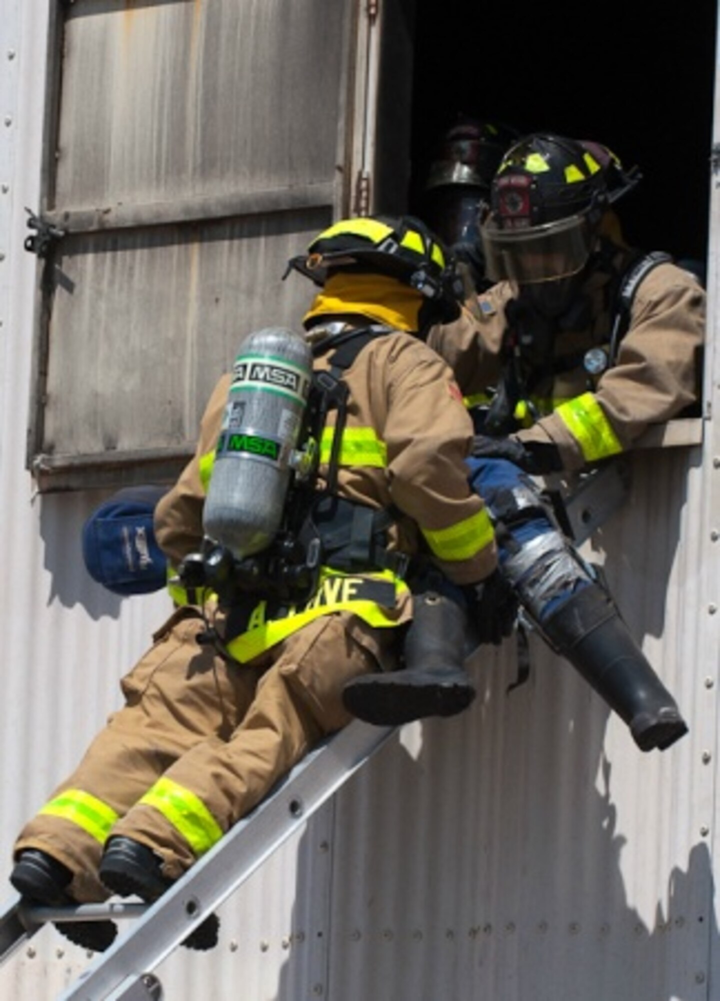 A military firefighter climbs a ladder to rescue one of three simulated victims caught in a live fire as part of a mission readiness exercise held recently at Holloman Air Force Base, N.M. (U.S. Army photo by Capt. John A. Brimley, 5th Armored Brigade, Division West Public Affairs)