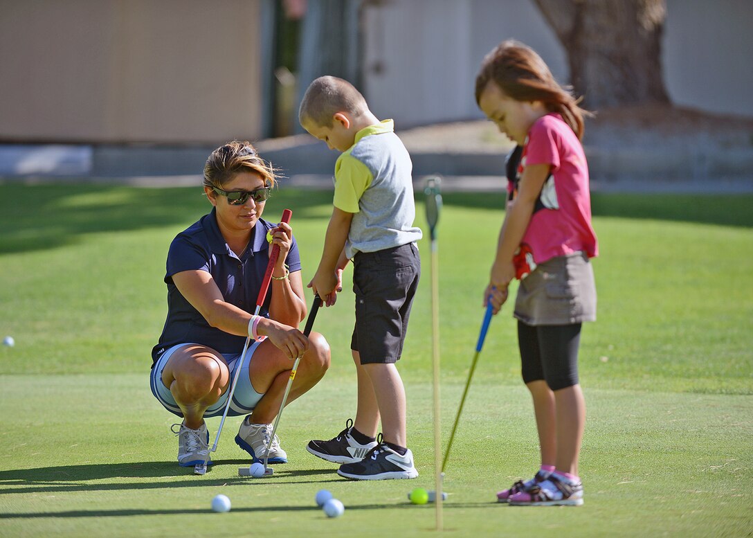 Chelsea Orozco (left), golf instructor, teaches children how to improve their putting skills during the annual junior golf camp held at Muroc Lake Golf Course July 22 to 24. (U.S. Air Force photo by Jet Fabara)