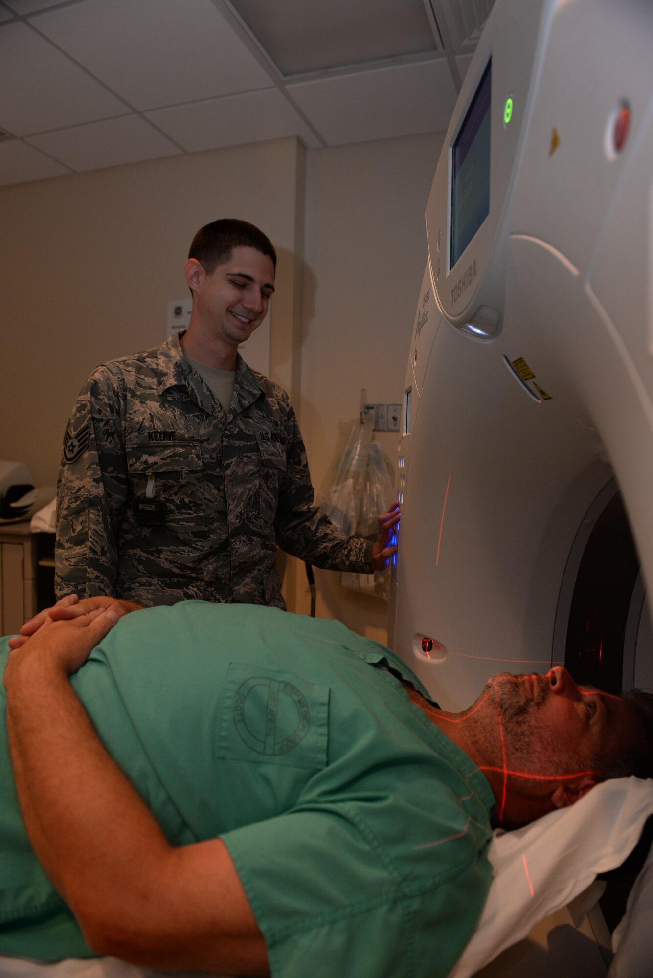 Staff Sgt. Justin Keune, 375th Medical Support Squadron Picture Archive Communication System Administrator, and Jerald Aylsworth, CAT Scan Quality Control Supervisor, show one position a patient can be scanned around the head, Scott Air Force Base, July 20, 2015. Keune processes an average of 45 patient records a day. (U.S. Air Force photo by Airman 1st Class Erica Holbert-Siebert)