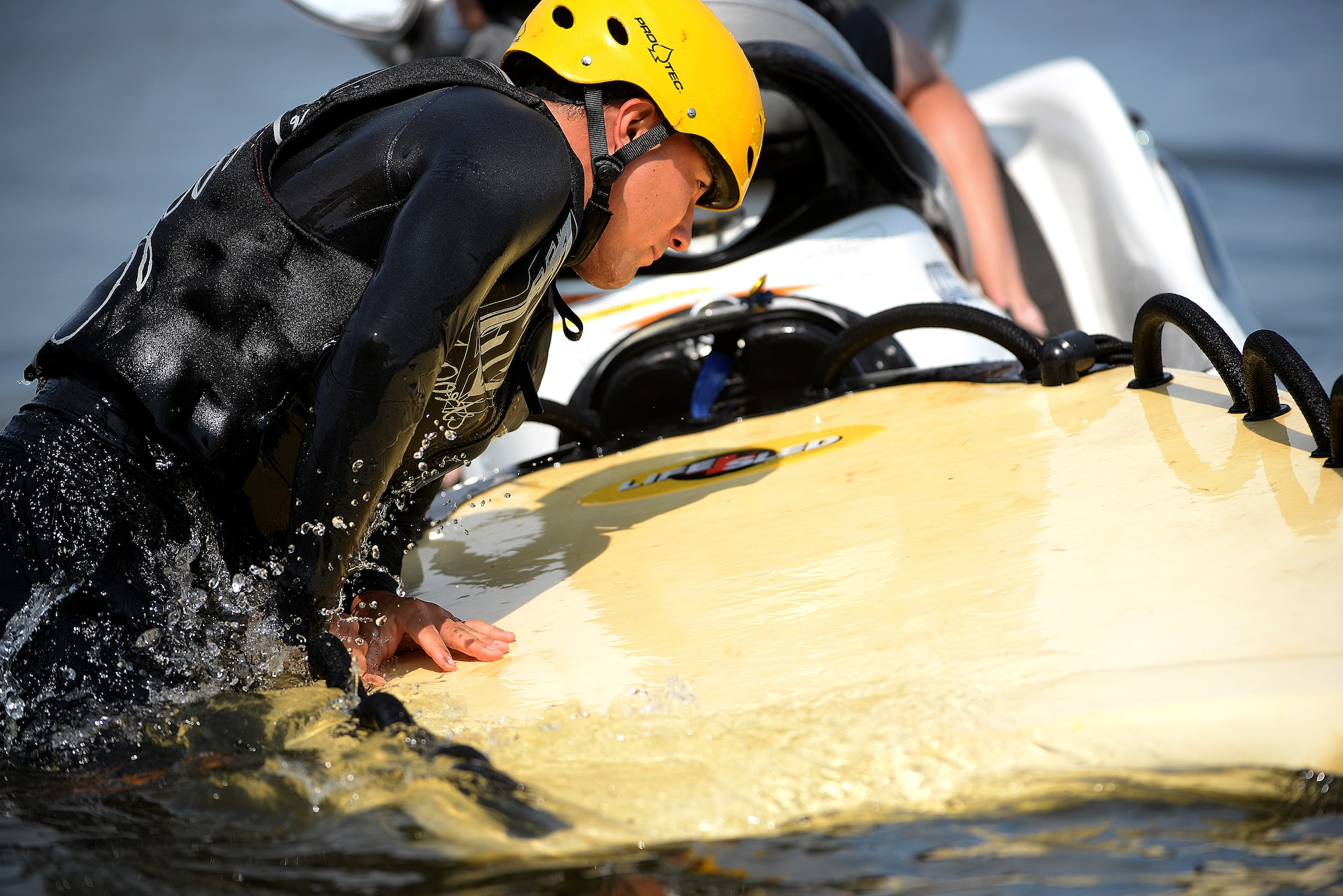 Capt. Kenneth Kaczmarek, 458th Airlift Squadron, climbs onto the back of a Sea-doo during the water survival training portion of the Survival, Evasion, Resistance, and Escape, or SERE, training July 16, 2015, at Carlyle Lake, Carlyle, Ill. Scott Air Force Base has a team of specialists that teach pilots and aircrew SERE techniques each month. The training is split up into two portions: combat survival training and water survival training. (U.S. Air Force photo/Senior Airman Jake Eckhardt)