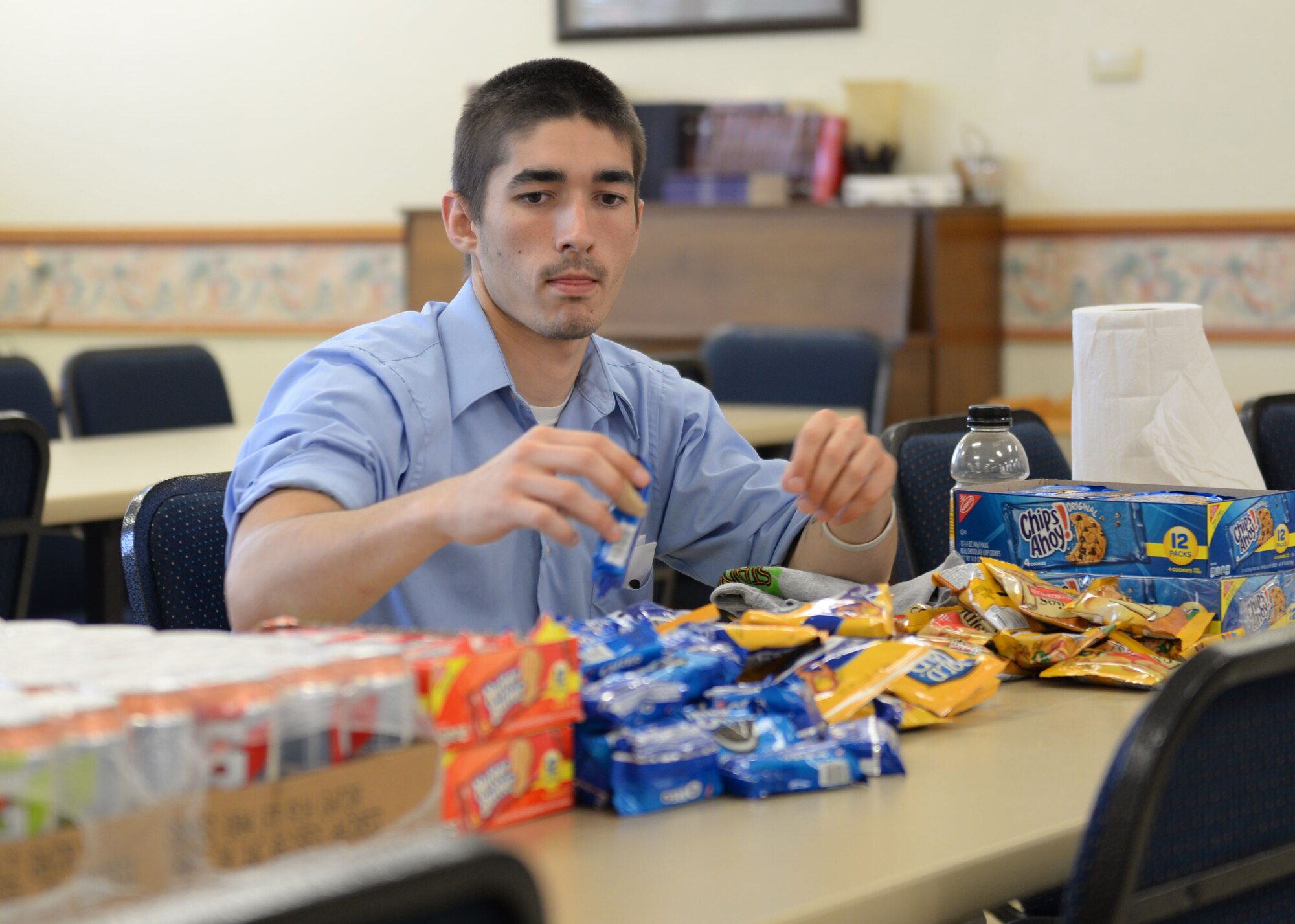 ALTUS AIR FORCE BASE, Okla. – Harrison Carnes, 97th Force Support Squadron arts and information specialist, reaches for a snack at the chapel activities room after donating blood at a blood drive, July 24, 2015. The quarterly blood drives are held to help give Airmen the oppurtunity to give back to the community. (U.S. Air Force photo by Airman 1st Class Kirby Turbak/Released)
