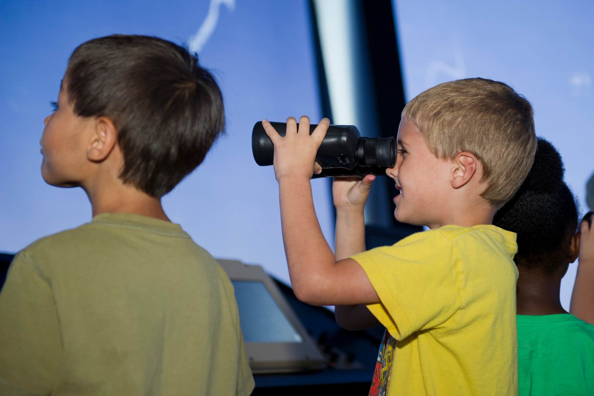A child from the Youth Activities Center looks through binoculars at the flightline during a tour of the air traffic control tower at Minot Air Force Base, N.D., July 24, 2015. Eleven children under the age of nine took an hour-long tour of the tower as one of their summer field trips. (U.S. Air Force photo/ Airman 1st Class Justin T. Armstrong)