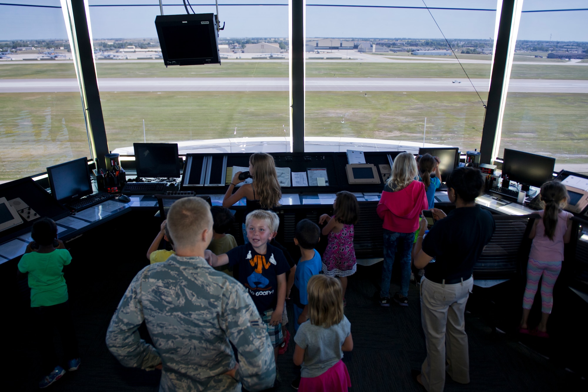 Children from the Youth Activities Center look through binoculars in the control room of the air traffic control tower at Minot Air Force Base, N.D., July 24, 2015.  After the training simulator, the children visited the control room on the top floor of the tower as the final stop on their tour. (U.S. Air Force photo/ Airman 1st Class Justin T. Armstrong)