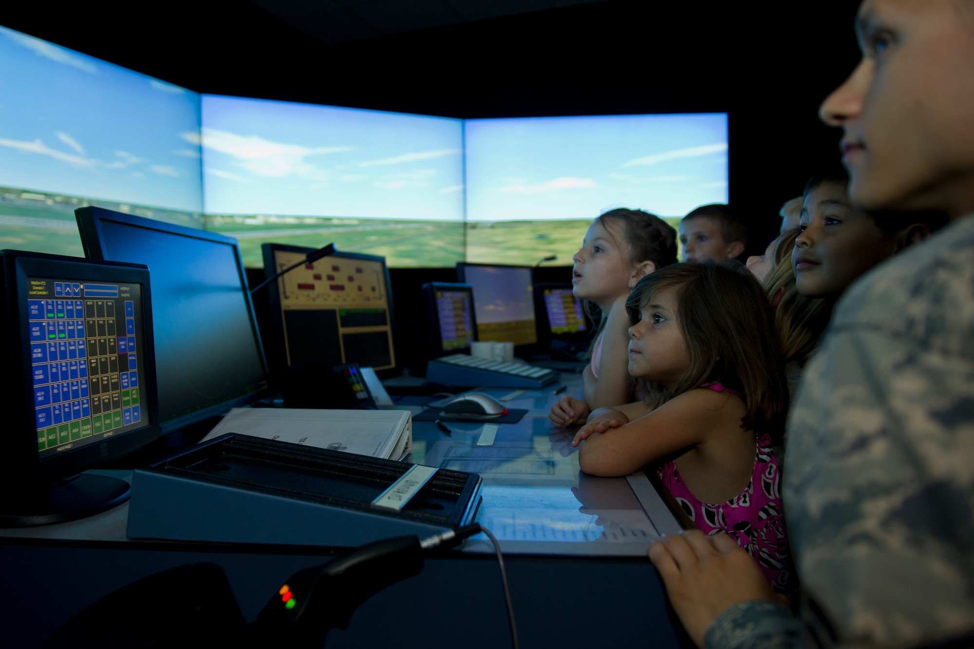 Airman 1st Class Daniel Langholz, 5th Operational Support Squadron air traffic control apprentice, watches a simulator with children from the Youth Activities Center at Minot Air Force Base, N.D., July 24, 2015. Eleven children under the age of nine toured the tower as one of their summer program field trips. (U.S. Air Force photo/ Airman 1st Class Justin T. Armstrong)