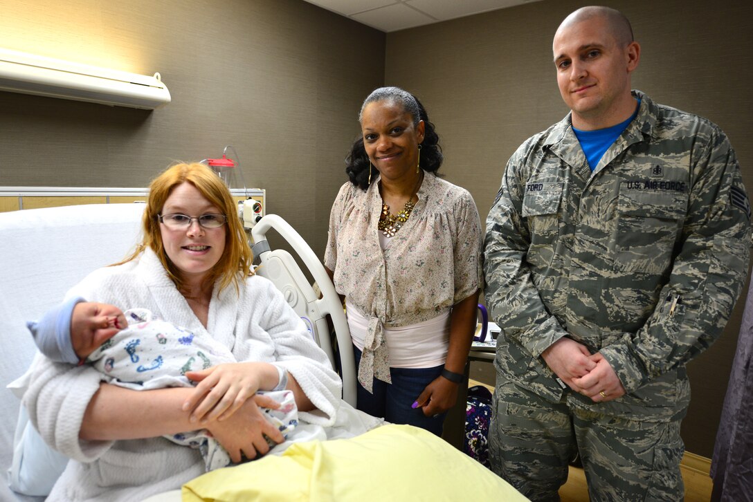 Lynette Lyles, 633rd Medical Support Squadron unit deployment manager, (center), and Staff Sgt. Lee Ford, 633rd MDSS outpatient noncommissioned officer in charge, congratulate Katie on the birth of Alexander at Langley Air Force Base, Va., July 16, 2015. Lyles and Lee assisted Katie with the birth just feet from USAF Hospital Langley in the hospital’s parking lot. (The last names of individuals in this photo were omitted for security purposes) (U.S. Air Force photo by Senior Airman Aubrey White/Released)