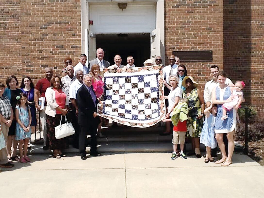 Quantico chapel members displaying a decorated handmade quilt for the victims at the recent Charleston shooting. The quilt was designed and sewn by Mrs. Carol Westin. 