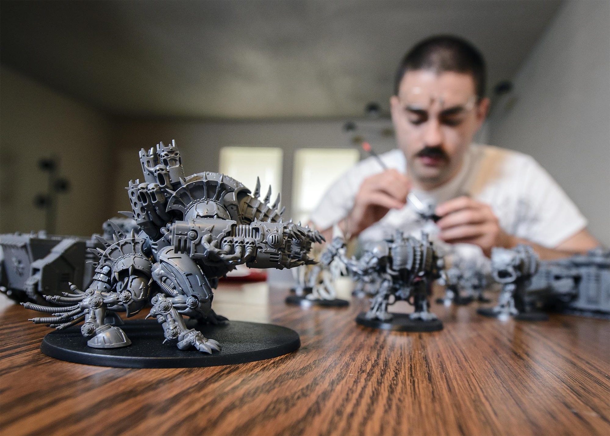 Senior Airman Thomas White, a 71st Operations Support Squadron Airman, enjoys some downtime as he customizes Warhammer 40,000 units at his home in Enid, Oklahoma, June 16. (U.S. Air Force photo by David Poe)