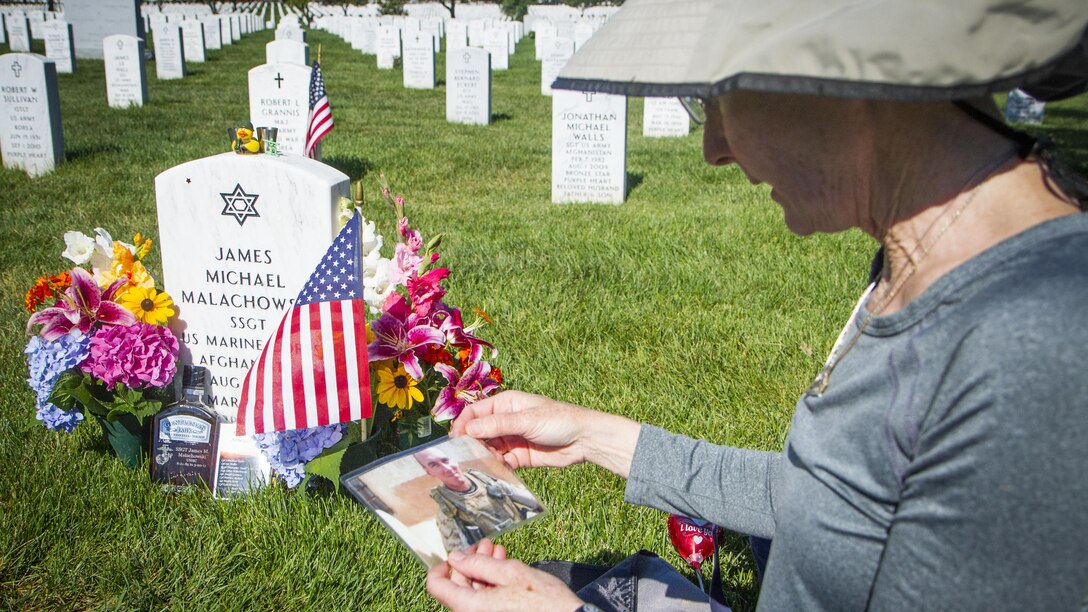 Alison Malachowski holds a photograph of her son, U.S. Marine Corps Staff Sgt. James Malachowski, in front of his grave in Section 60 of Arlington National Cemetery, July 22, 2015. Staff Sgt. Malachowski, who was with the 2nd Battalion of the 8th Marines, was killed by an improvised explosive device during his fourth combat depoloyment on March 20, 2011, while his unit was raising the Afghanistan national flag over a small compound near Patrol Base Dakota in Marjah Province. "He died a terrible, painful death," said Alison. "But he did not scream or cry and I know why - it was so he wouldn't frighten his guys." (U.S. Army photo by Sgt. Ken Scar)