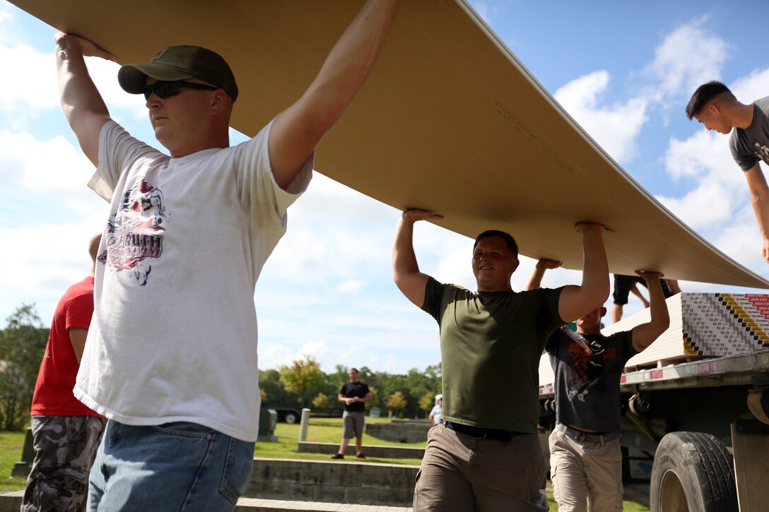 Marines lend a helping hand moving dry-wall during a veterans home build volunteer activity at Pamlico County, North Carolina, July 27, 2015. Marines with Marine Wing Communications Squadron 28 volunteered to assist in the construction of a home being built for Marine Corps veteran Warren Cottrell and his family. The volunteer event gave the Marines the opportunity to help better their community, while establishing relationships with other members of their squadrons outside of their work environment.