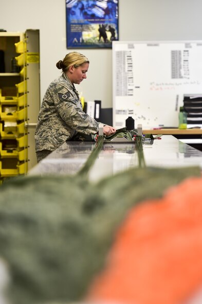 Staff Sgt. Ambyr Lalone, 1st Special Operations Support Squadron aircrew flight equipment craftsman, inspects parachute lines prior to re-packing on Hurlburt Field, Fla., July 23, 2015. Aircrew flight equipment Airmen support Hurlburt’s flying squadrons by packing BA-22 parachutes designed for emergency bail-out. (U.S. Air Force photo/Senior Airman Jeff Parkinson)