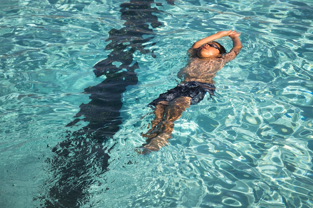 Anthony Barba, 8, son of 1st Sgt. Roberto Barba Jr., first sergeant, 3rd Battalion, 11th Marine Regiment, practices swimming the backstroke during swimming lessons held at the Combat Center Training Tank, July 27, 2015. Learning to swim is something that is available to patrons of any age or fitness level. (Official Marine Corps photo by Pfc. Levi Schultz/Released)